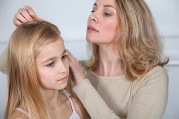 Woman inspecting child's scalp